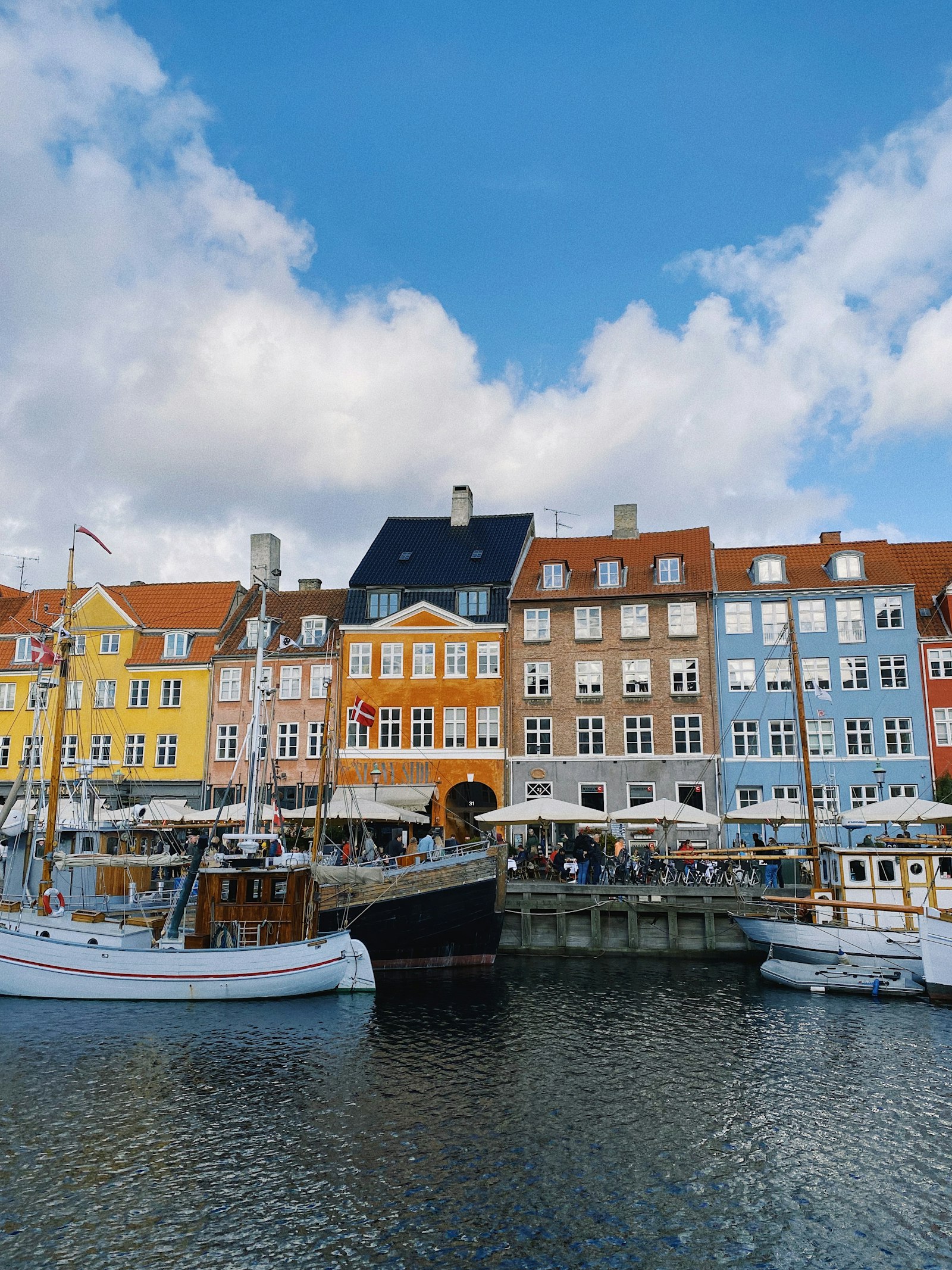 The colourful gabled houses and moored wooden boats of Copenhagen's Nyhavn harbour under a blue sky